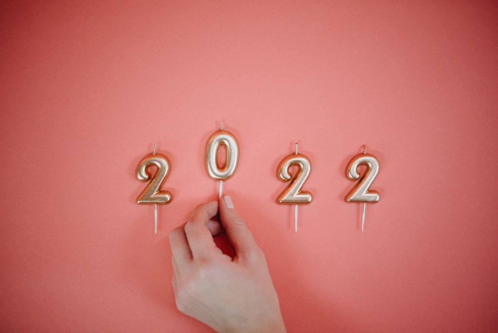 Graphique rose avec des bougies dorées 2022 et une main sur le zéro. Année passée en revue